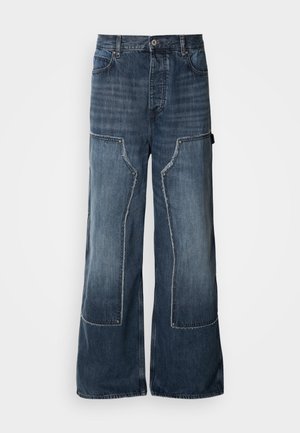Pantalones vaqueros holgados de denim azul con piernas anchas, que presentan detalles de patchwork, costuras en contraste, grandes bolsillos laterales y un cierre de botón.