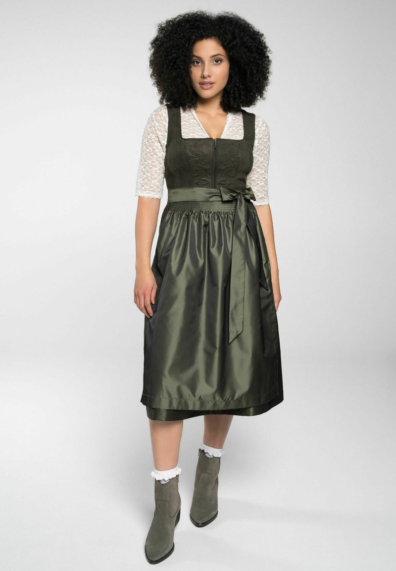 Grünes Dirndl-Kleid mit strukturiertem Oberteil, Spitzenärmeln und einem gerafften Satins Rock. Verfügt über eine Schleife in der Taille und einen Reißverschluss vorne.