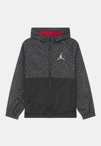 Chaqueta con capucha negra con un patrón salpicado en blanco y rojo. Presenta un cierre con cremallera al frente, puños elásticos y un logo en el pecho.