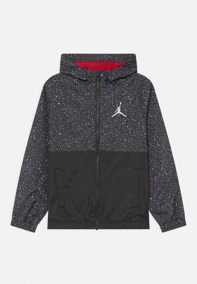 Chaqueta con capucha negra con un patrón salpicado en blanco y rojo. Presenta un cierre con cremallera al frente, puños elásticos y un logo en el pecho.