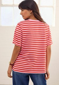 Rood en roze gestreepte T-shirt met korte mouwen, relaxte pasvorm en ronde halslijn, gecombineerd met blauwe jeans.