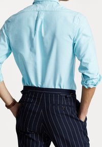 Ljusblå skjorta med uppvikta ärmar, tillsammans med mörkblå pinstripebyxor med sidofickor och en skräddarsydd passform.