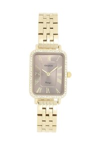 Montre rectangulaire dorée avec un cadran brun clair, des chiffres romains et des accents de strass. La conception du bracelet à maillons ajoute de la texture.