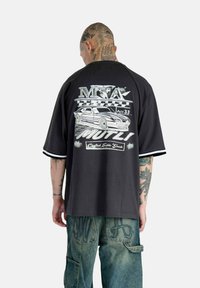 Black oversized t-shirt with a graphic of a car and text on the back. Short sleeves with white stripes, made of a soft material.