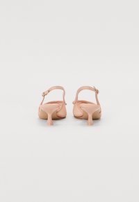 Nude slingback pete z visokim petam in gladko teksturo, z vitkim gležnjem in razširjenim mačjim petam. Preprost dizajn, brez vzorcev ali akcentov.