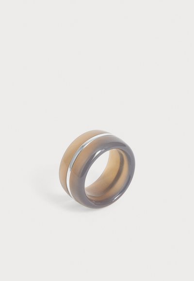 Large bague bicolore avec des bandes translucides marron et grises séparées par une fine bande argentée brillante, présentée sur un fond clair uni.