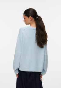 Pull bleu clair avec un col rond et une coupe décontractée. Le tissu est lisse, avec des poignets et un ourlet côte, ainsi que des épaules tombantes pour un confort accru.