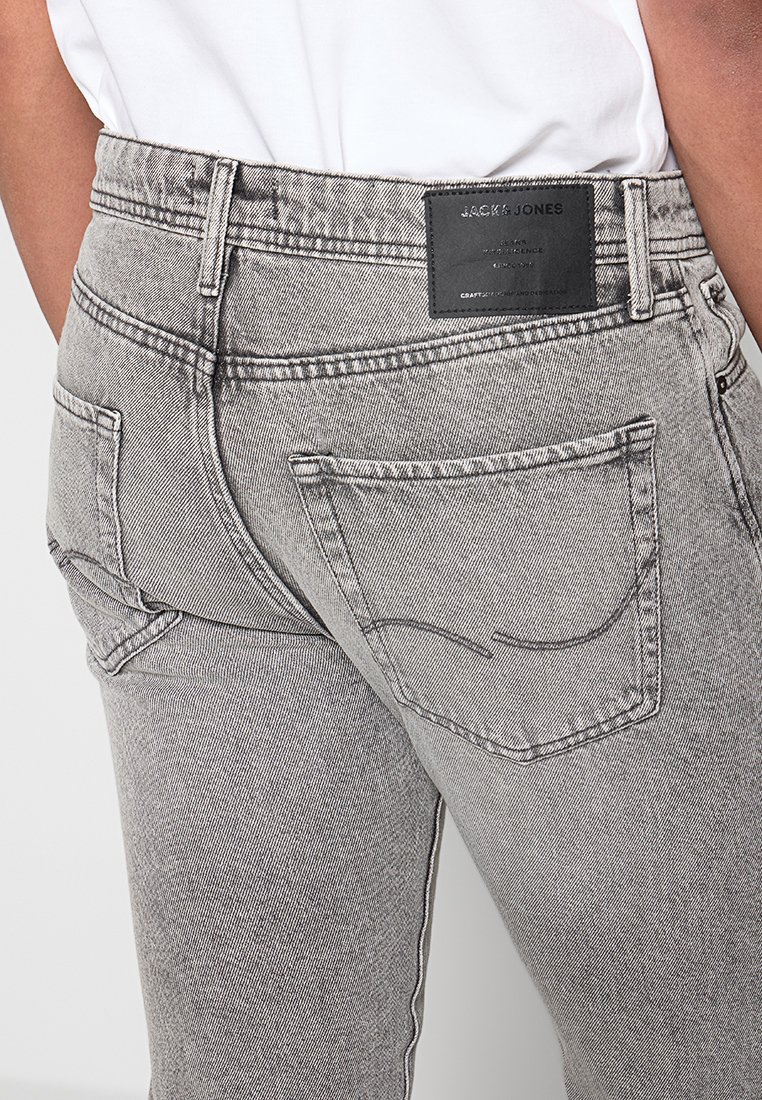 Graue Jeans aus Denim mit einer strukturierten Oberfläche, ausgestattet mit einem schwarzen Logopatch am hinteren Bund und zwei Gesäßtaschen mit gebogener Naht.