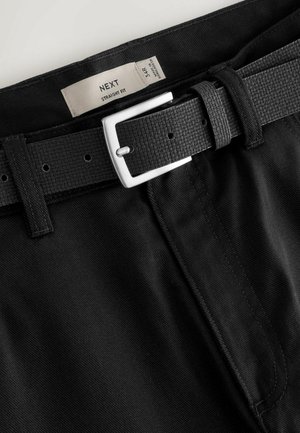 Čierne nohavice rovného strihu s textúrovaným čiernym opaskom a striebornou prackou. Viditeľná nálepka so veľkosťou 34R. Materiál má jemné diagonálne pruhy.