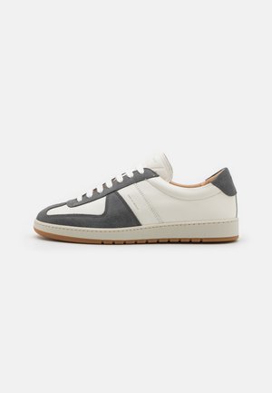 Niedrig geschnittene Sneaker aus einer Kombination von weißem Leder und grauem Wildleder. Gummisohle mit einfacher Schnürung und gepolsterter Kante.