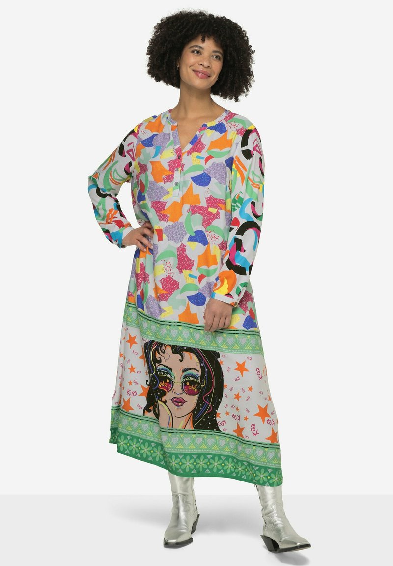 Farbiger, langärmeliger Kleid mit abstrakten Formen in mehreren Farben. Der untere Teil zeigt ein großes grafisches Gesicht und einen dekorativen Rand.