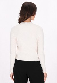 Hellbeige geripptes Sweatshirt mit langen Ärmeln, rundem Halsausschnitt und Rüschensaum, aus einem weichen Strickmaterial gefertigt, mit subtiler Textur.