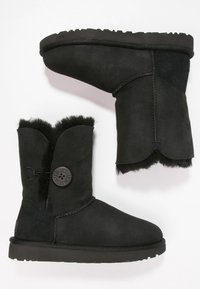 Bottes mi-mollet en daim noir avec détail bouton et doublure en shearling douillet, semelle en caoutchouc plate et coutures latérales.