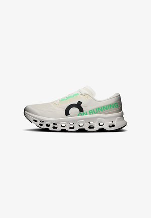 Chaussure de course blanche avec logo "On Running" noir et vert, présentant une semelle épaisse et ventilée ainsi que des lacets blancs, vue de profil.