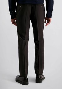 Broek van donkerbruin stof met een subtiele textuur, voorzien van platte zakken en een recht ontwerp. Gecombineerd met glanzende zwarte schoenen.