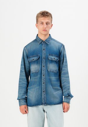 Denim shirt in medium blue with a button-up front, two chest pockets, long sleeves, and a classic collar; slightly faded texture.