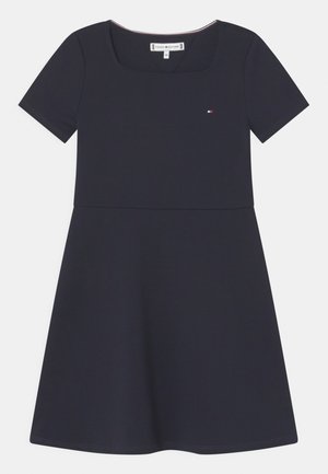 Marineblå kjole med korte ærmer, firkantet udskæring, tætsiddende talje, udvidet skørt og lille Tommy Hilfiger-logo på brystet.