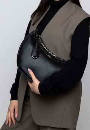 Black leather handbag with a curved shape, featuring a braided chain strap and a small tag. Smooth texture with a subtle grain pattern.