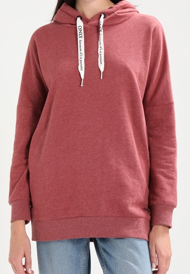 Ruskotoinen huppari valkoisilla nyöreillä, jossa lukee "VAIN koska se on intohimo," käytettynä vaaleansinisien farkkujen kanssa.