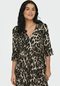 Robe imprimée léopard avec un col en V, des manches trois-quarts et un ourlet volanté. Fabriquée en un matériau doux et léger. Comprend des accents en dentelle.