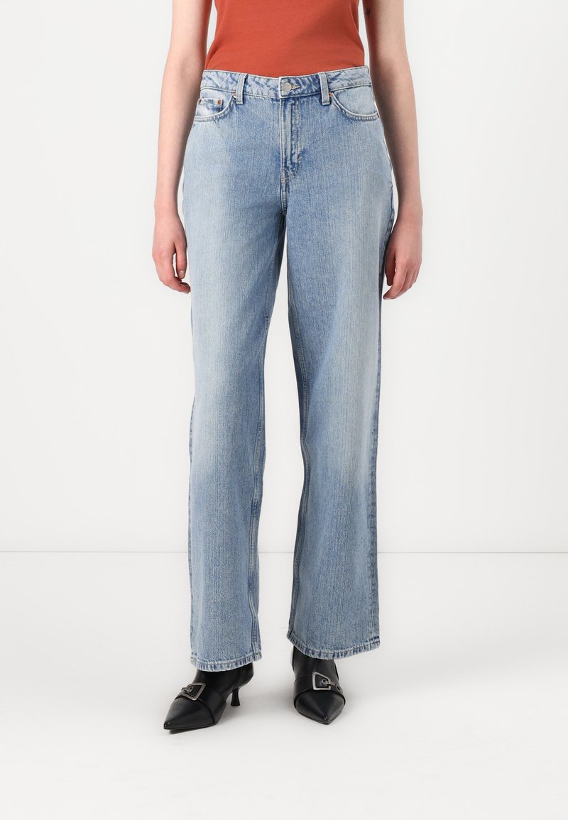 Jean large bleu clair en denim, avec une taille haute, cinq poches et une fermeture à glissière avec bouton. Texture lisse.