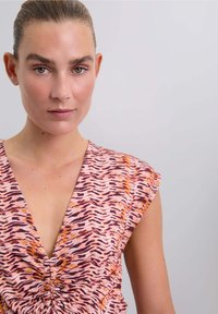Blusa fantasia in rosa, arancione e viola con scollatura a V profonda e dettaglio arricciato al centro, caratterizzata da maniche corte a campana.