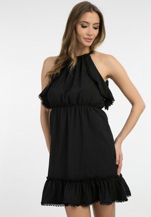Zwarte halterjurk met ruche-nek en -zoom, gestructureerde stof, elastische taille en decoratieve kantafwerking langs de onderrand.