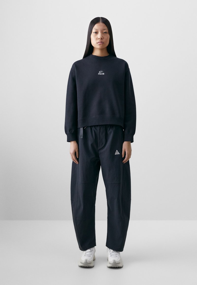 Navy blue sweatshirt with a round neckline and logo on the chest, paired with loose-fitting navy pants featuring side pockets and logo accents.