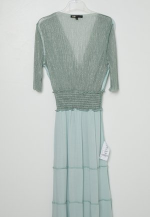 Robe vert clair avec haut transparent texturé, manches trois-quarts, taille élastique et jupe fluide suspendue sur un cintre transparent.
