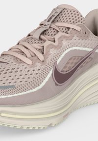 Ροζ αθλητικό παπούτσι Nike για τρέξιμο με αναπνεύσιμο πλέγμα στο επάνω μέρος, αποσβεσμένη σόλα και σκούρο μωβ λογότυπο Nike στο πλάι.