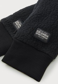 Sorte fleecehandsker med struktureret stof og ribbede manchetter. Har et vævet mærke med teksten "Columbia Sportswear" i hvid og sort.