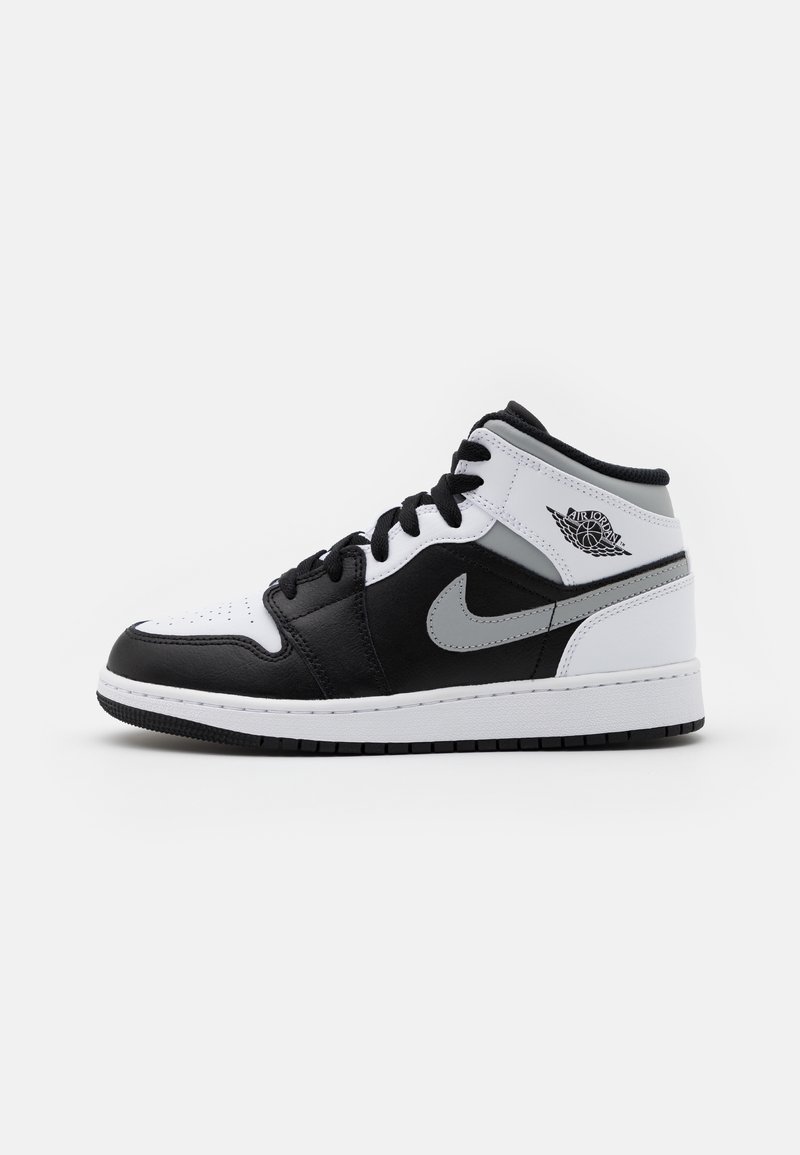 Basket montante avec panneaux en cuir noir, blanc et gris, lacets noirs, logo Nike swoosh et logo Air Jordan wings sur le côté.