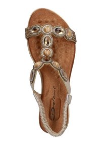 Beige sandaal met een gestructureerde bruine binnenzool, decoratieve steenaccenten en een gevlochten band. Ontworpen met een T-bar vorm en platte zool.