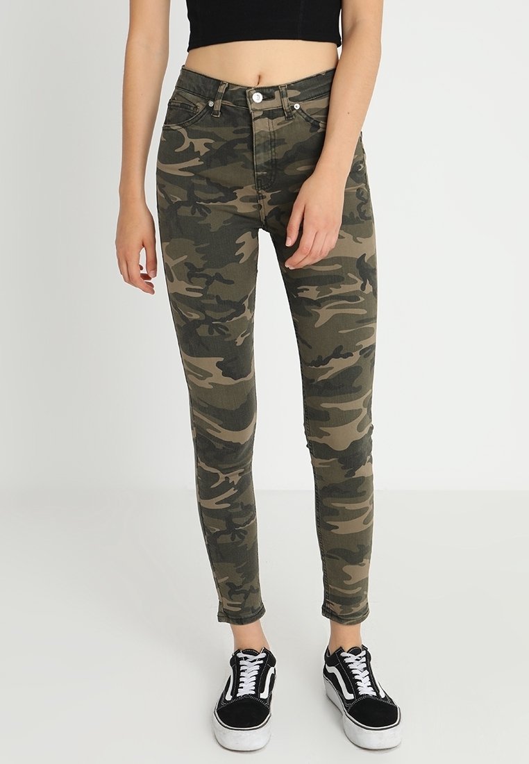 Kamouflage skinny jeans i gröna och bruna nyanser, med fem fickor, dragkedja med knappstängning och en åtsittande passform. Kombineras med svarta sneakers.