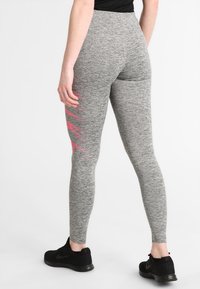 Leggings atletici grigi con una texture melange, caratterizzati da una striscia diagonale rosa sul lato esterno della coscia. Completati da un'alta vita.