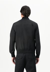 Black bomber jacket with ribbed collar and cuffs, smooth fabric, zip and side pockets, featuring a plain design without patterns.