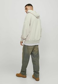 Lys grå oversized hoodie med snøre i hætten. Båret med løse jeans i blå nuancer og brune støvler. Glat stof, afslappet pasform.