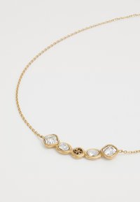 Gouden ketting met vijf heldere edelstenen van verschillende vormen, voorzien van een delicate ketting en een kleine decoratieve medaille in het midden.