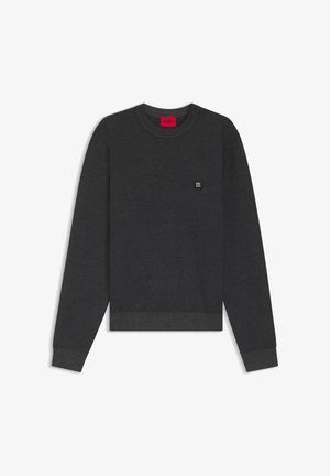 Szürke kötött pulóver kerek nyakkivágással, texturált mintával és egy kis logóval a bal mellrészen. Bordázott mandzsettákkal és szegéllyel rendelkezik.