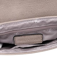 Indvendigt på en grå faux lædertaske med en glat foring, en lynlåslomme og et mærke med præget branding.