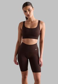 Smeđi rebrasti sportski brus i set kratkih hlača viskog struka. Napravljen od teksturirane tkanine s uskim krojem i suptilnim logotipom na pojasu.