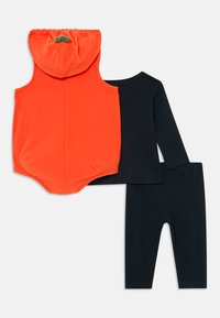 Orange sleeveless hooded romper with green stem detail paired with black long-sleeve top and black leggings laid flat.
