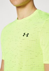 Pánské sportovní tričko s krátkým rukávem v neonově žluté barvě, se strukturovaným designem a černým logem Under Armour na hrudi.