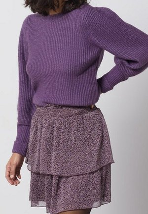 Paarse geribbelde gebreide trui met lange mouwen, gecombineerd met een gelaagde paarse rok met bloemenprint, voorzien van een elastische tailleband en zachte stof.
