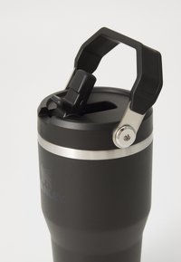 Black insulated travel mug with a silver band, a flip-top opening, and a sturdy handle; smooth texture with a matte finish.