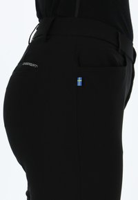 Zwarte broek met een gladde textuur, voorzien van een klein blauw en geel vlag embleem, een achterzak en een logo op de tailleband.