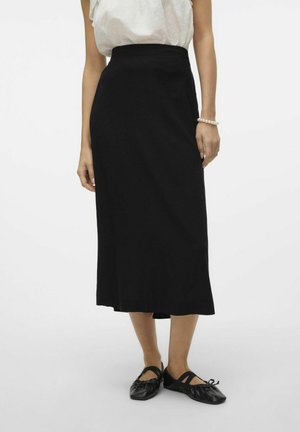 Czarna spódnica midi wykonana z gładkiej tkaniny, z wysokim stanem i prostym, luźno opadającym krojem. W połączeniu z czarnymi płaskimi butami.