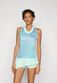 Lyseblå sportslig tanktop med V-hals, lagdelt volangkant og korte matchende bukser. Har subtile logodetaljer og et stilrent design.