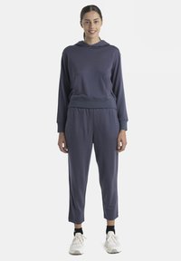 Haut à capuche bleu marine avec poche kangourou, accompagné d'un pantalon de jogging fuselé assorti. Tissu lisse avec poignets ajustés.
