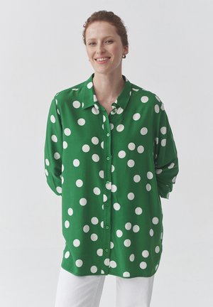 Camicia verde a maniche lunghe, con grandi pois bianchi, colletto e un fit morbido. Realizzata in tessuto leggero.